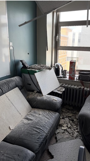 On distingue des morceaux de béton, dont un gros près du téléphone, tombés du plafond. Une personne se trouvait sur le divan lors des événements.