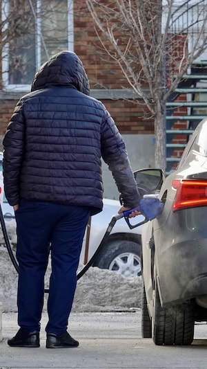 Un homme met de l'essence dans sa voiture.