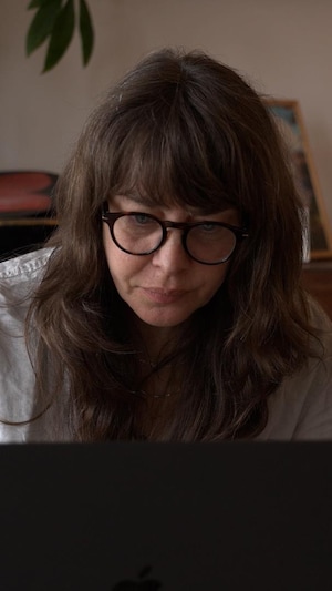 Deux femmes sont assises à une table devant un ordinateur portable. Elles regardent l'écran. 