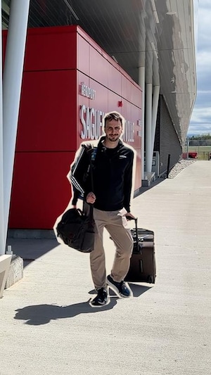 Un homme tire une valise en marchant.