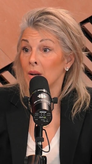 Une femme avec une veste noire parle à un micro.