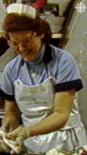 Femme en uniforme coupe des petits poissons avec des ciseaux pour les mettre en conserve.