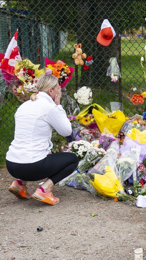 Une femme se recueille devant un amas de fleurs près des lieux du drame survenu samedi soir à Vancouver. 
