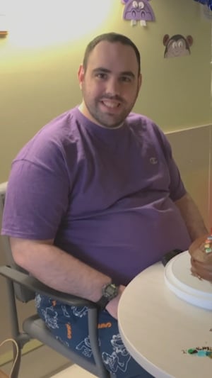 Sébastien à l'hôpital devant un gâteau d'anniversaire.
