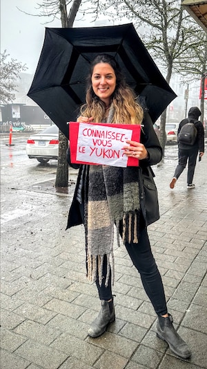 La journaliste Chloé de Périgny tient une pancarte sur laquelle on lit : Connaissez-vous le Yukon?
