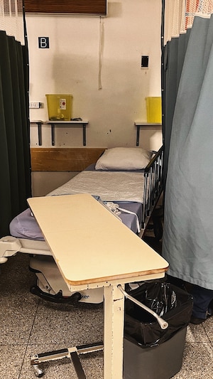 Une civière vieillissante, séparée par des rideaux, qui doit être remplacée.