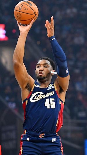 Un joueur de basketball décoche un lancer devant deux adversaires. 