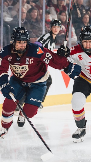 Deux joueuses de hockey se disputent pour arriver en premier à la rondelle pendant un match.