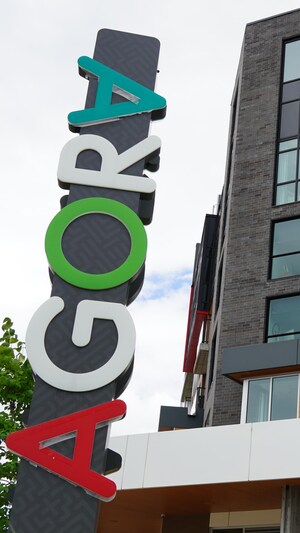 Un grand signe vertical pour AGORA près d'un édifice à logements.