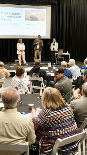 Des personnes assises autour de tables rondes dans un salle. 