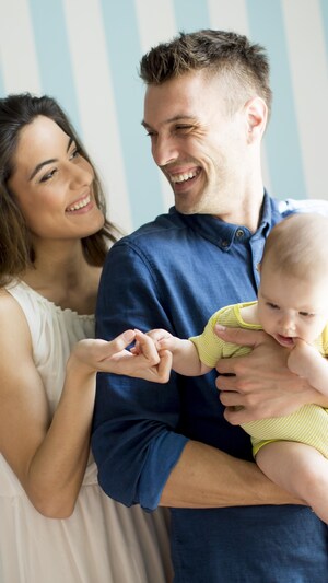Young family with a baby standing by the wall