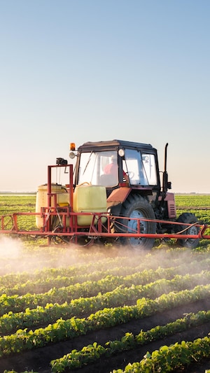 Un tracteur avec à l'arrière des tuyaux déverse un produit dans un champ.