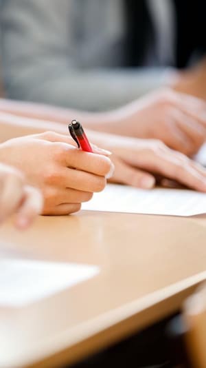 Une fille tient un crayon devant une feuille de papier.