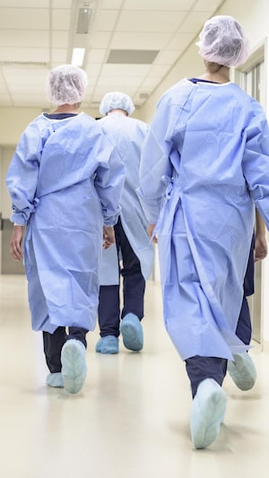 Des infirmières marchent de dos dans le corridor d'un hôpital.  