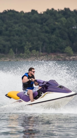 Jeune homme en train de conduire une motomarine lors d'une journée d'été sur un lac.