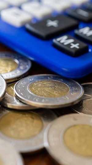 Des pièces de 2 dollars canadiens sur une table, à côté d'une calculatrice.