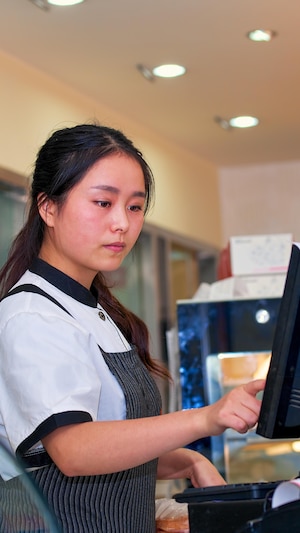 Une adolescente asiatique travaille dans une épicerie. 