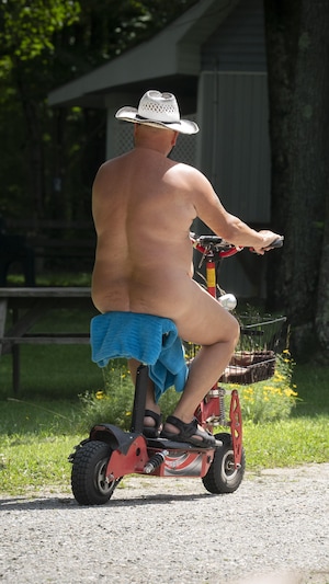 Une personne naturiste circule nue sur un cyclomoteur. 