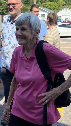 Louise Brissette à l'extérieur avec des gens derrière.