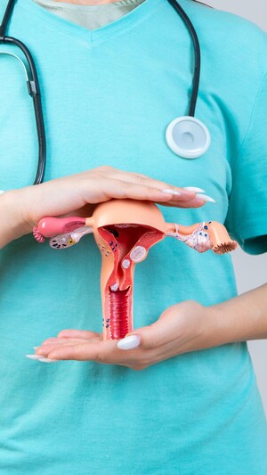 Une femme qui tient un modèle du système reproducteur féminin dans ses mains.