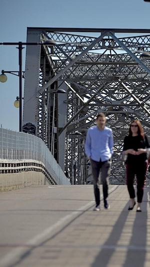 Des piétons et un cycliste circulent sur le pont Alexandra. 