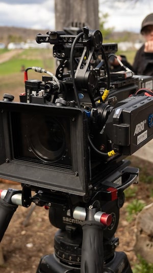 Une caméra sur un plateau de tournage boisé.