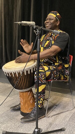 Un homme assis qui joue du djembé dans un studio de radio.