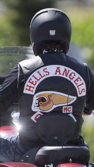 Un homme à moto de dos avec une veste des Hells Angels.