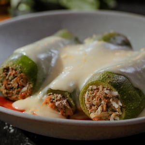 Des courgettes farcies, sauce au citron et aux oeufs servies dans une grande assiette ronde.