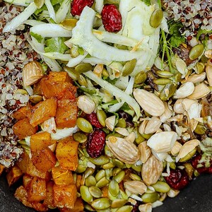 Bol de quinoa tricolore comprenant des noix de grenoble, des graines de citrouille, des amandes, des canneberges, des champignons, du fenouil, et des cubes de citrouilles.