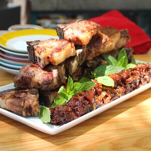 Côtelettes d'agneau avec confiture aux dattes et bacon, et ketchup maison dans une assiette blanche.