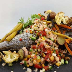 Un poisson entier recouvert de crevettes et de légumes.