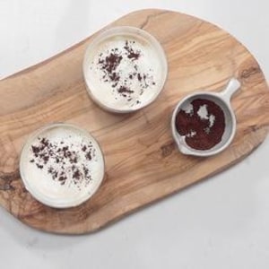 Deux bols de café sont sur une planche de bois.