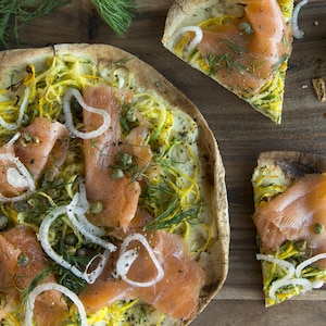 Une pizza avec des oignons, des câpres et de l'aneth.