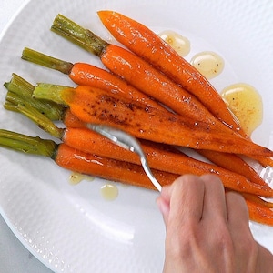 Des carottes avec un partie du feuillage, dans une assiette.