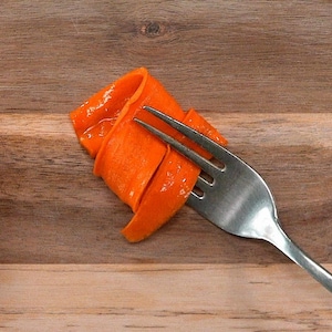 Une tranche de carotte confite enroulée sur une fourchette.