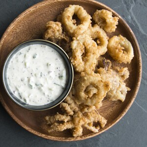 Le bol de sauce est dans une assiette à côté des calmars frits.
