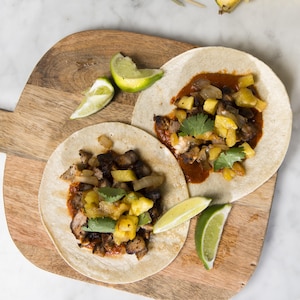 Deux tacos sont disposés sur une planche de bois.
