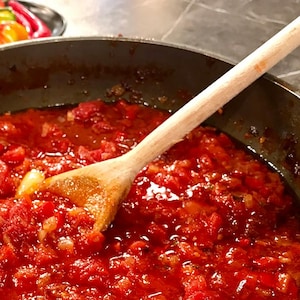 Une grande poêle remplie de sauce tomate avec une cuillère en bois.