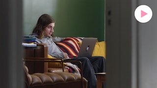 Le comédien Sam-Éloi est assis dans un salon. Il regarde un ordinateur, placé sur ses jambes. 