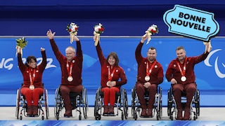 Les cinq membres de l'équipe canadienne de curling en fauteuil roulant souriants avec leur médaille, à côté du logo « Bonne nouvelle » de MAJ.