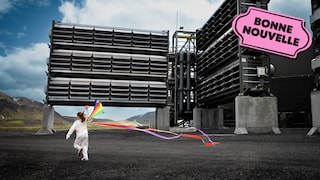 Une fille joue avec un cerf-volant multicolore devant un usine avec beaucoup de ventilateurs, à côté du logo de la bonne nouvelle de MAJ.