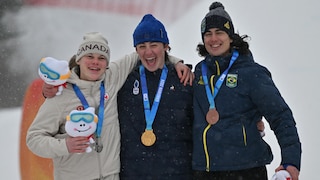 Trois jeunes athlètes masculins sourient avec leurs médailles.