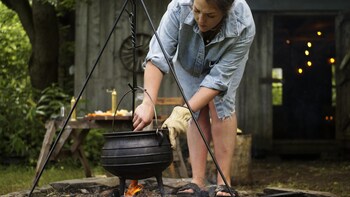 Frédérike de Folks and Forks mélange le contenu d'une marmite en fonte au dessus d'un feu de camp.