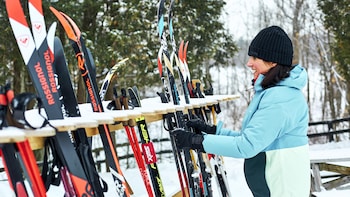 Geneviève O'Gleman dehors en hiver qui dépose des skis de fond sur un support.