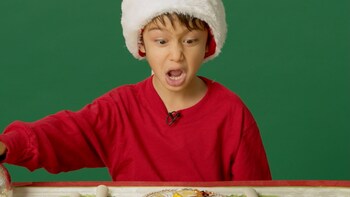 Un enfant avec un chapeau de noël découvre une portion d'aspic dans une assiette.