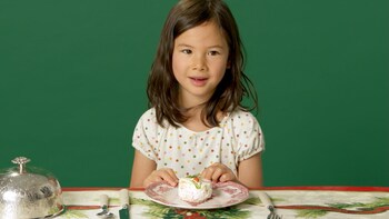 Une petite fille devant une assiette contenant une portion de pain sandwich.