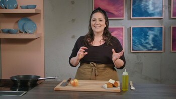 Derrière un ilot de cuisine, une personne explique comment couper une pomme pour ajouter ces morceaux dans une vinaigrette.