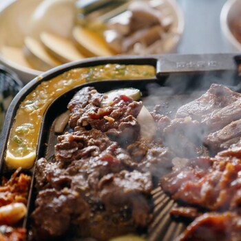 Un BBQ coréen sur lequel cuit plusieurs morceaux de viande.