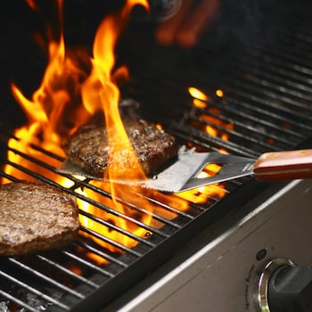 Des boulettes de viande hanchée qui cuisent sur une grille de barbecue.